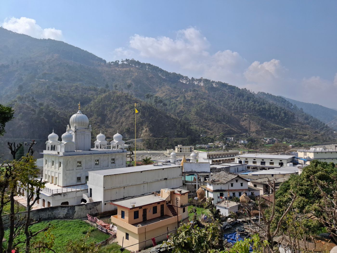 Gurdwara surrounded by picturesque mountain landscape under a clear blue sky.